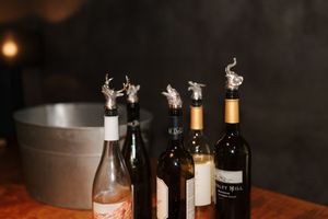 Collection of dark liquor bottles and glasses arranged on a wooden surface in dim lighting.