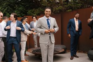 Wedding party wearing gray and navy suits poses together during outdoor celebration at garden venue.