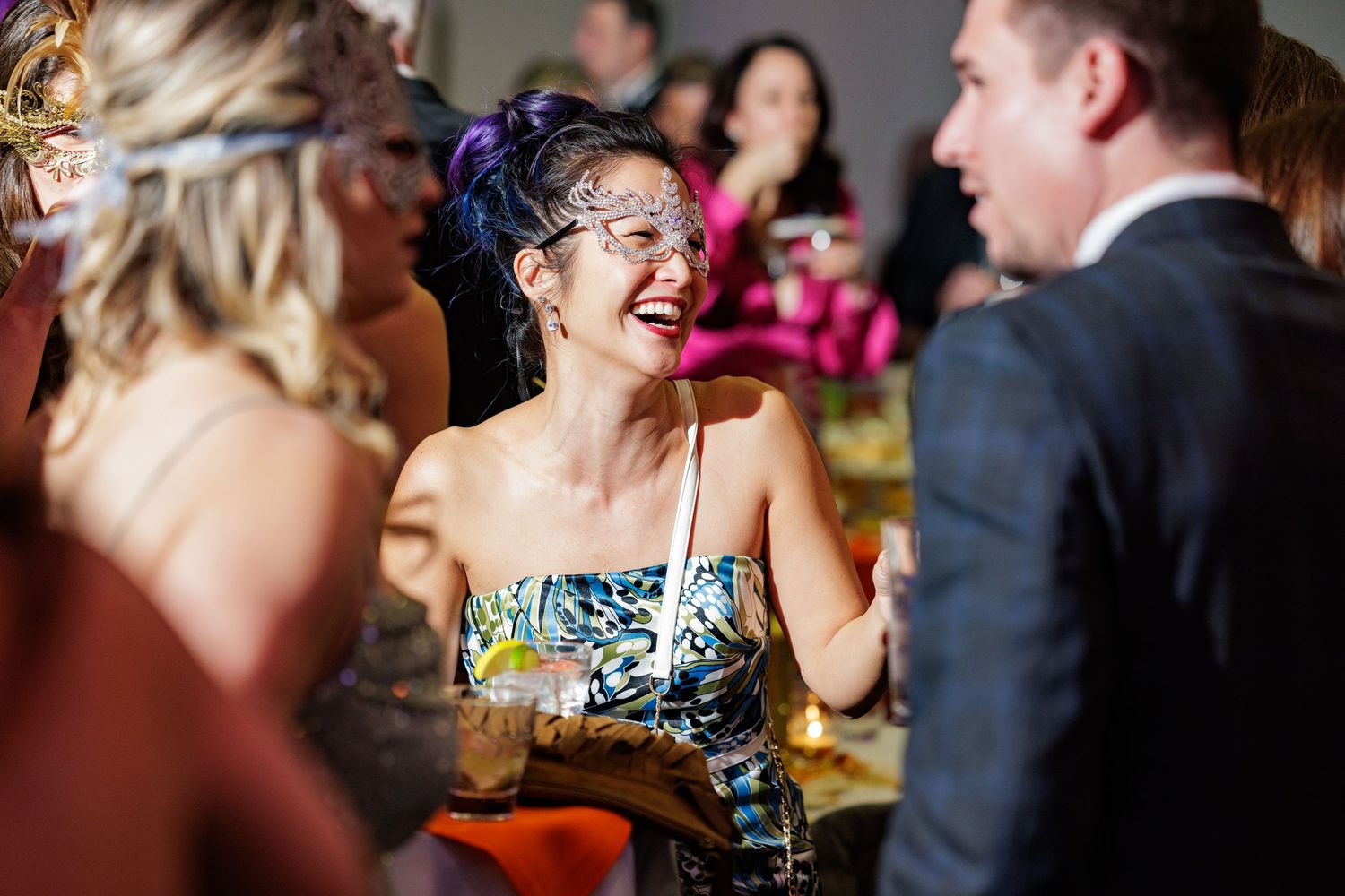 People enjoying conversation and laughter at a social gathering in a dimly lit venue.