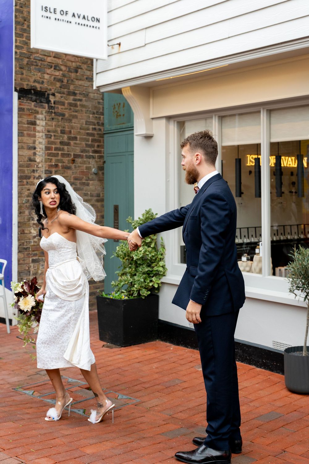 A playful dance sequence between a couple in formal wedding attire on a brick patio outside a venue.