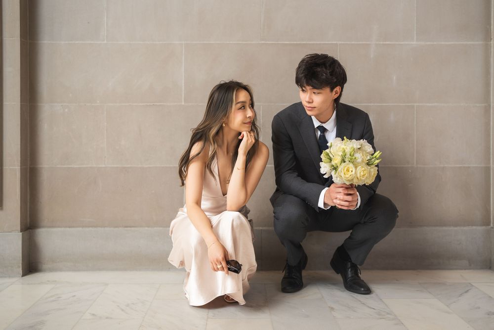 A couple sits together on stone steps in formal attire during a wedding photo session.