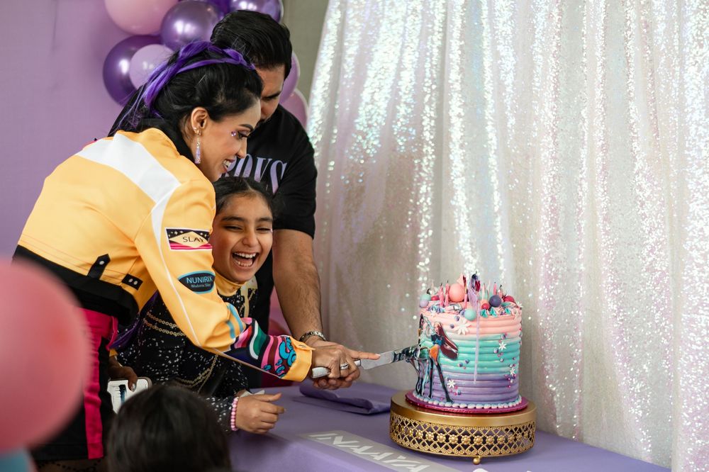 A birthday celebration with purple decorations and a cake on the table surrounded by party guests.