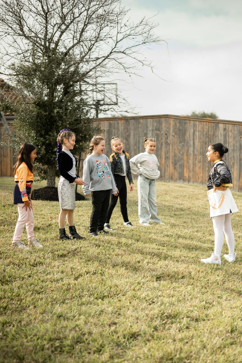 Students stand in a line on a grassy hillside during an outdoor activity on a cloudy day.