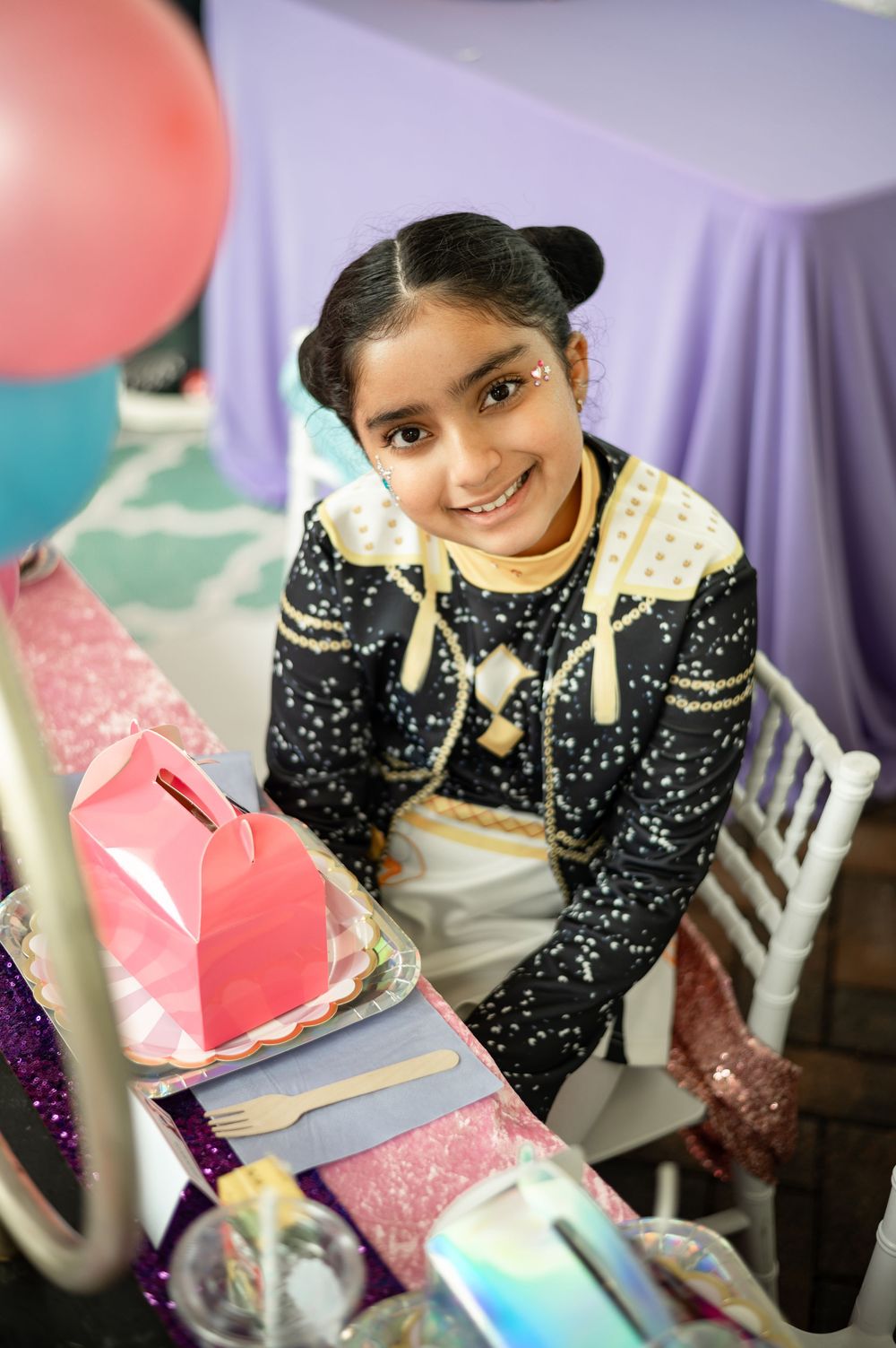 Student wearing sparkly jacket studies with colorful books and papers on desk in purple-tinted learning environment.