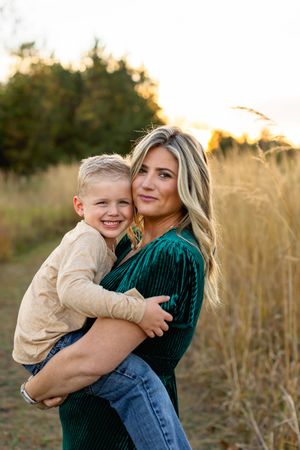 Candid outdoor family photos showing loving embraces against a backdrop of tall grass at sunset.