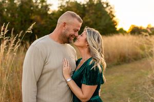 A couple shares a romantic moment at sunset in a golden field of tall grass.