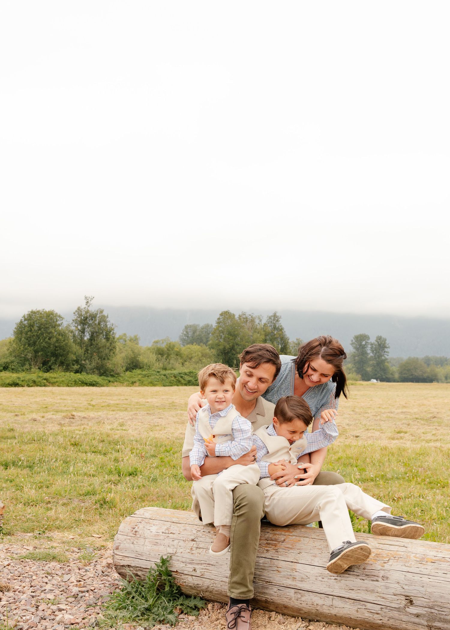 Family spending quality time together while sitting on a fallen log in a sunny meadow during a summer afternoon.
