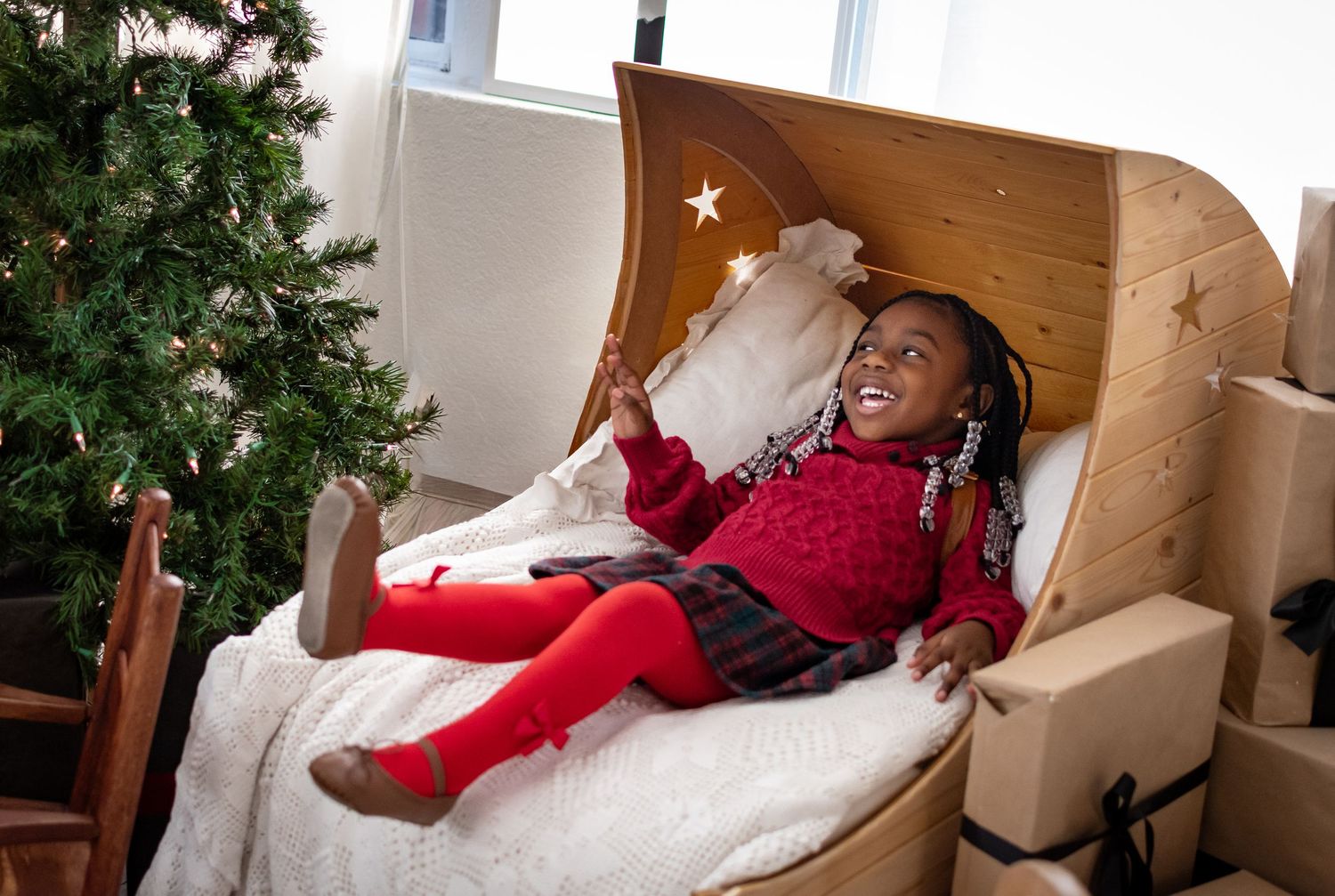 Smiling child in cozy wooden Christmas bed setup at Tacoma studio