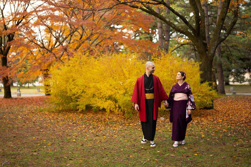 Couple dressed in traditional Japanese kimono strolling through a park with brilliant fall foliage.