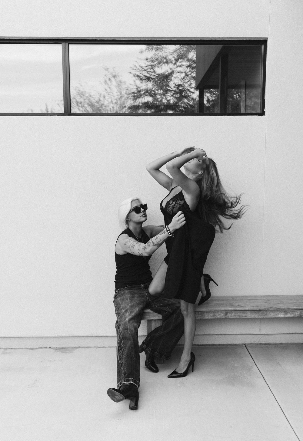 Black and white photo sequence showing figure in dark clothing sliding down against white wall in four progressive stages.