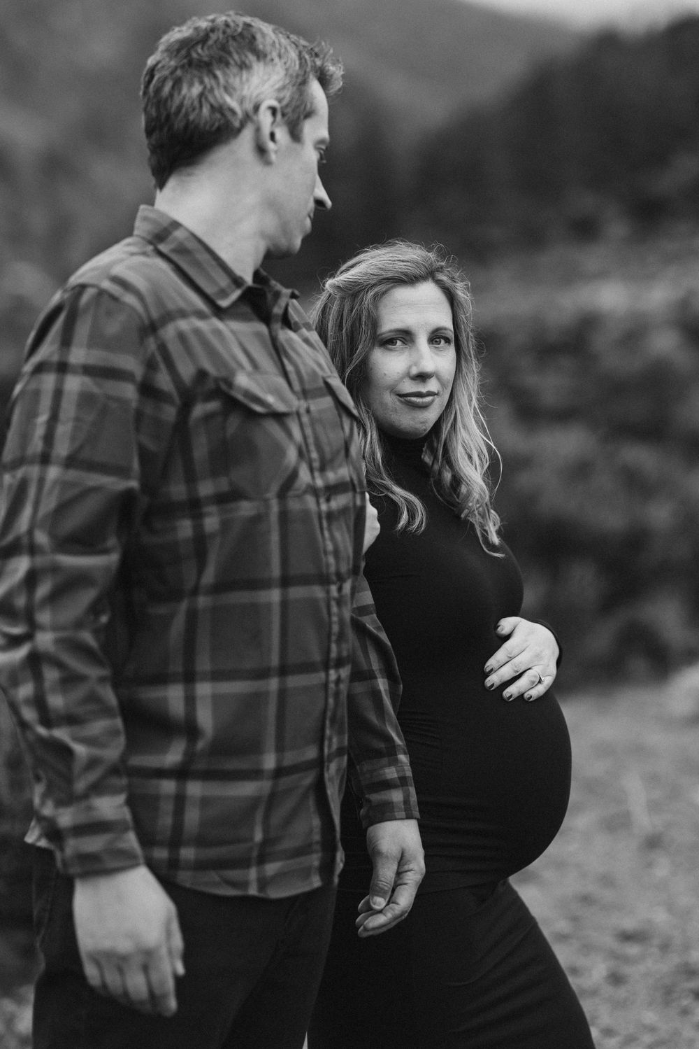 Black and white portrait session with couple in plaid shirt and dark dress.