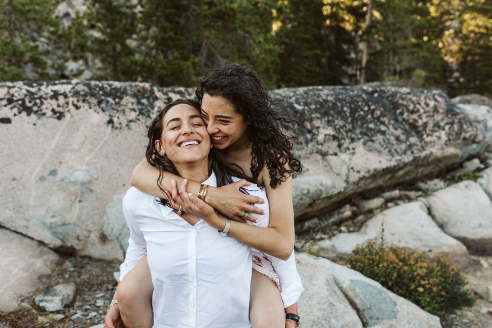 Playful piggyback ride moment captured outdoors against rocky landscape.