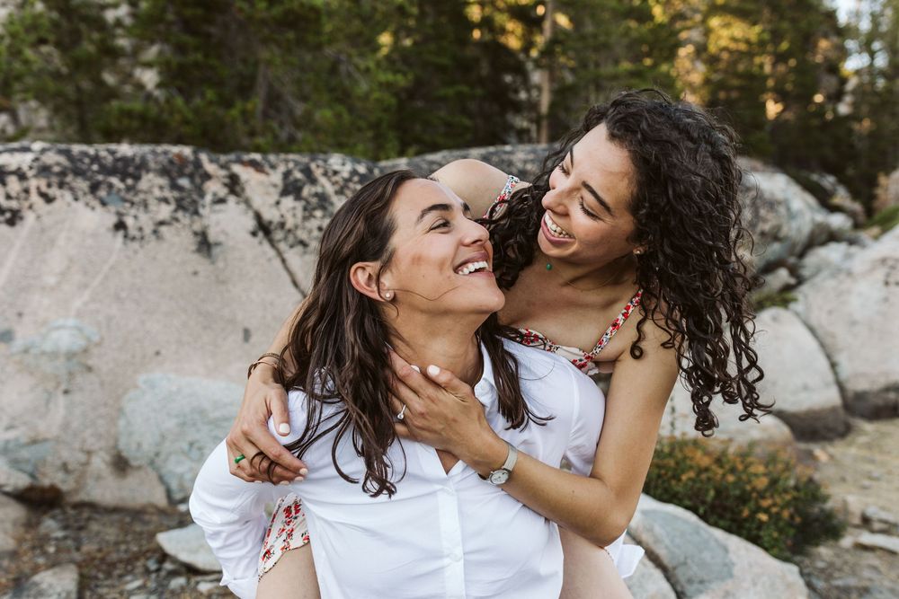 Candid moment of laughter and embrace captured in natural outdoor setting.