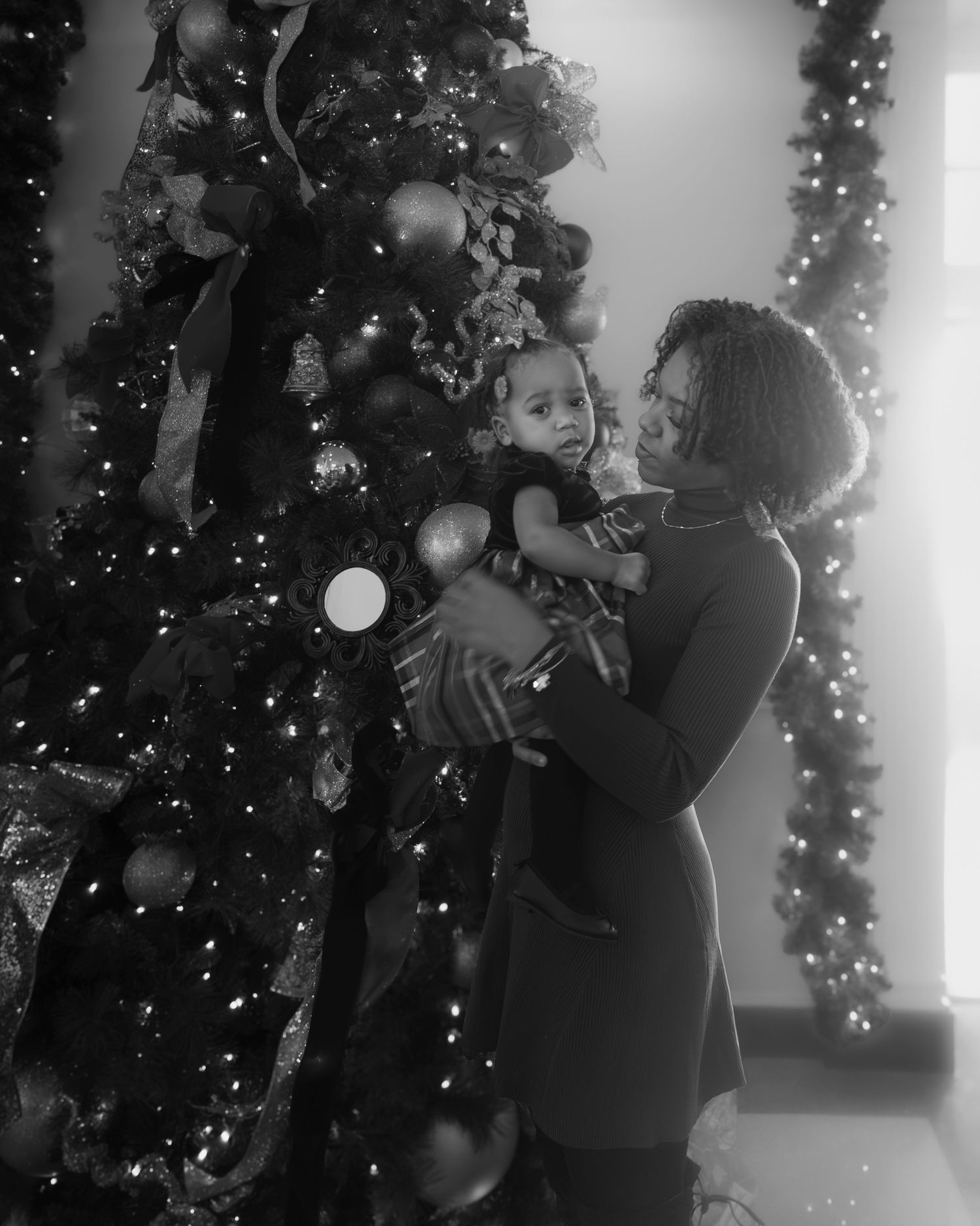 Black and white photo sequence showing a couple embracing in front of a decorated Christmas tree with twinkling lights.