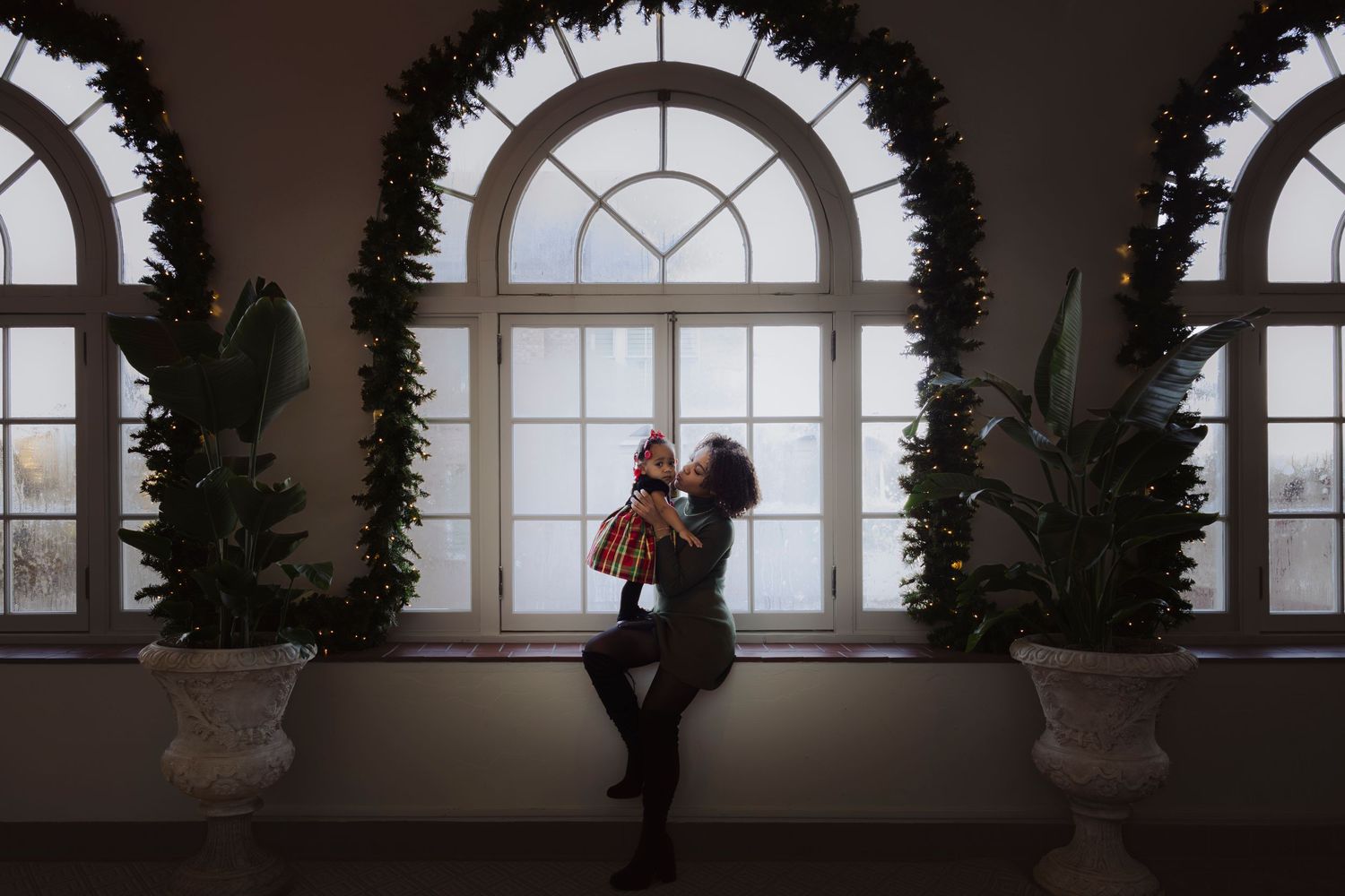 A silhouetted figure stands in an arched window hallway with dramatic lighting and shadows.