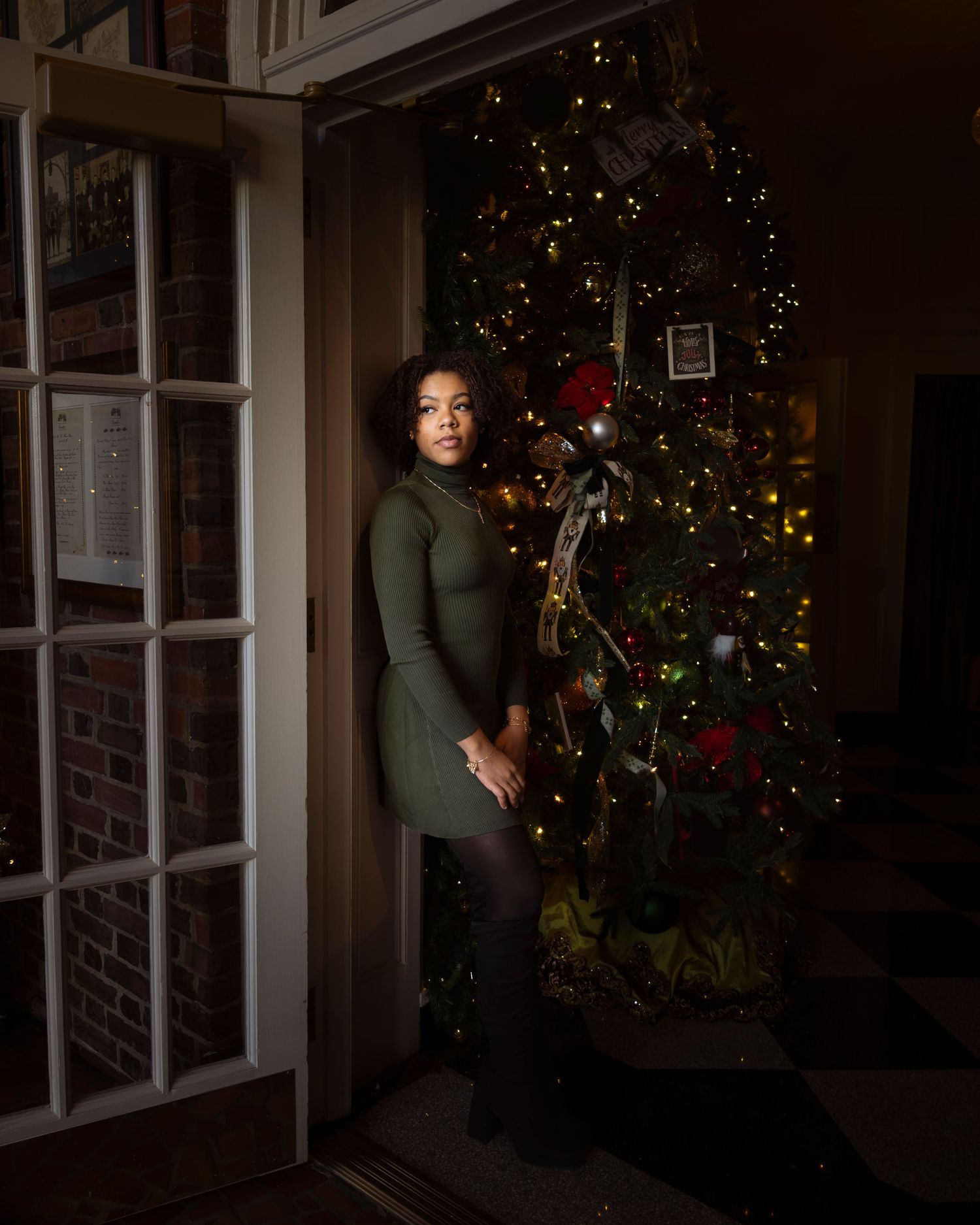 A dark and moody photo series showing a person standing near a decorated Christmas tree at night.