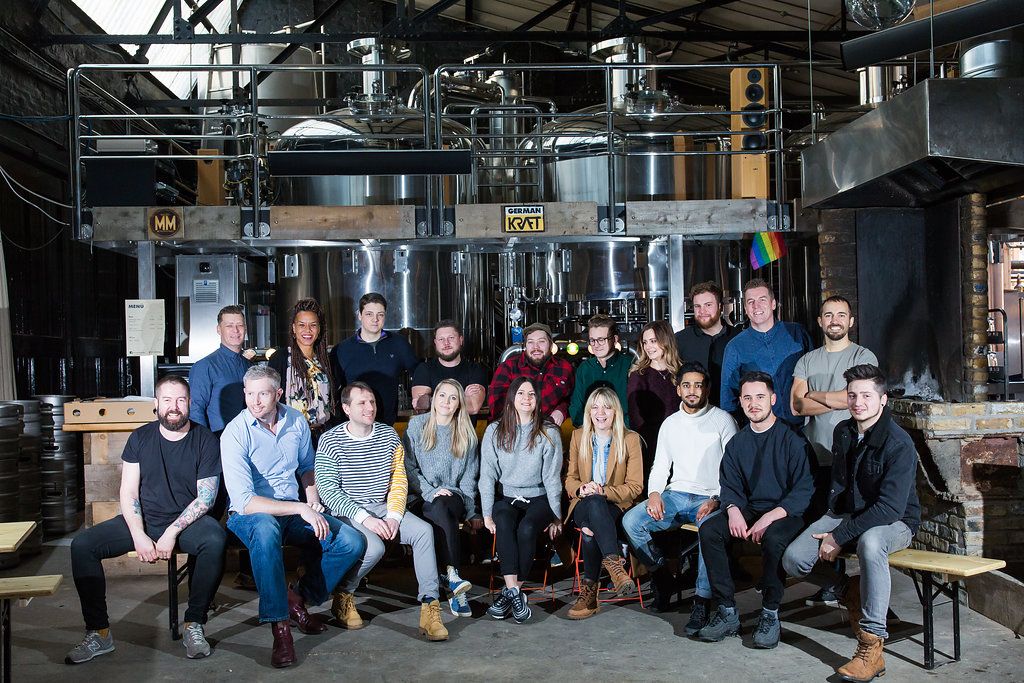 Large group of professionals posing together in industrial office space with exposed ceiling.