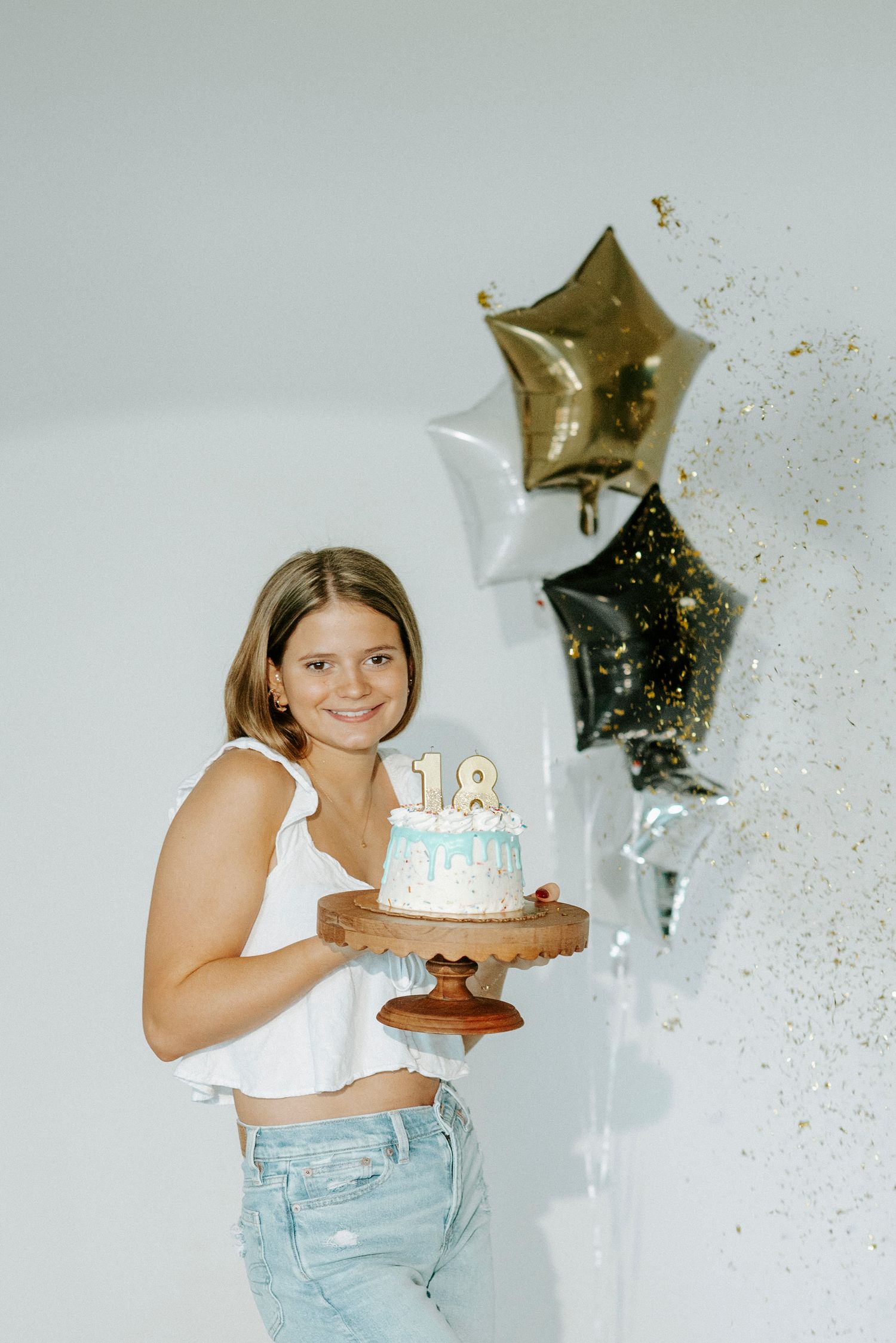 Birthday celebration with cake showing number 18 and decorative star balloons against white background.
