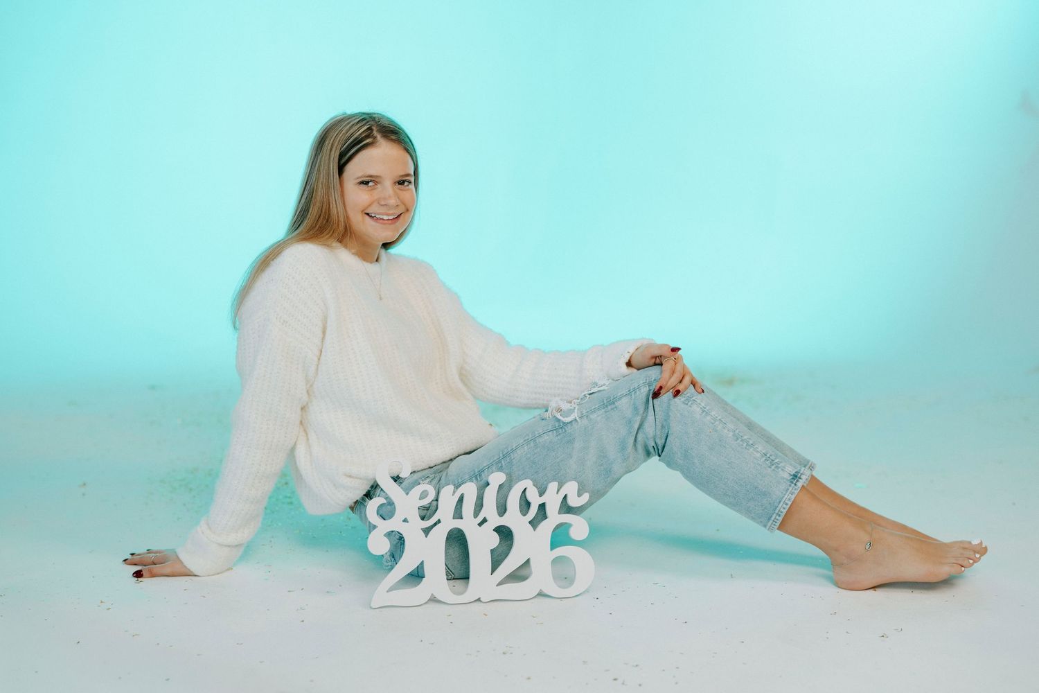 Person in white sweater lounging on light blue background in various relaxed poses during photo session.