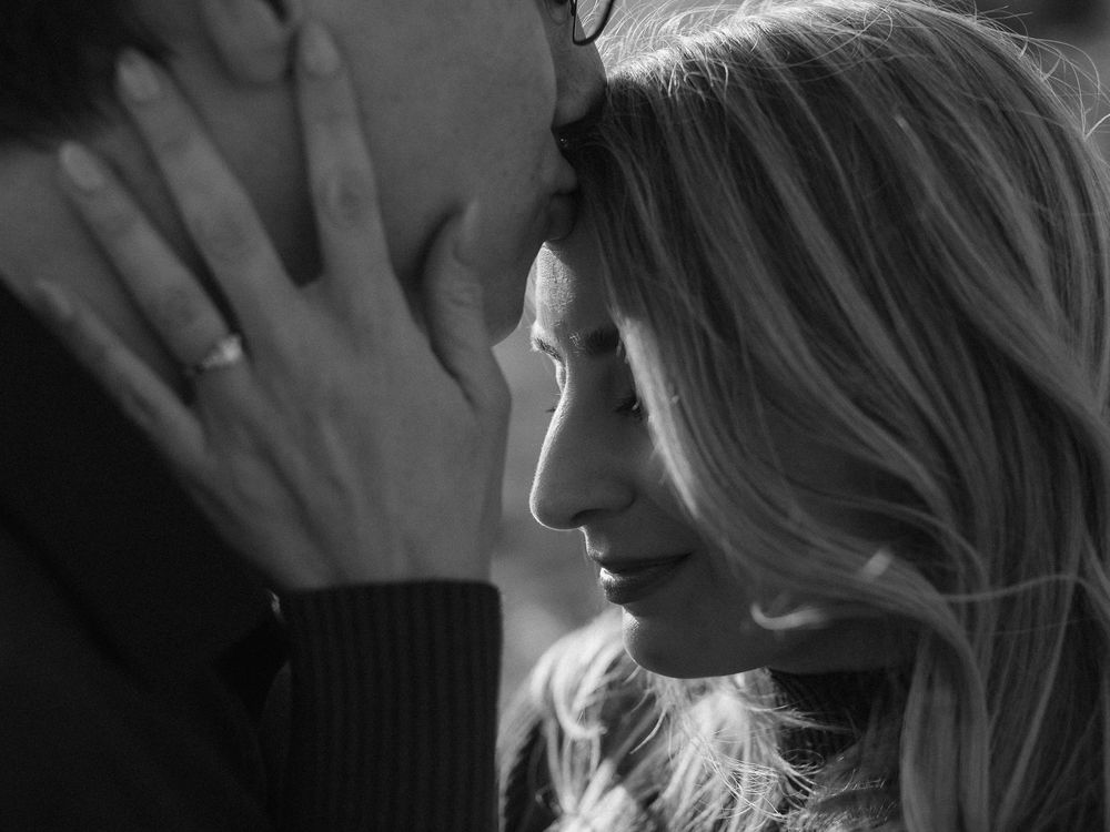 A black and white intimate close-up portrait of two people in a tender romantic moment.