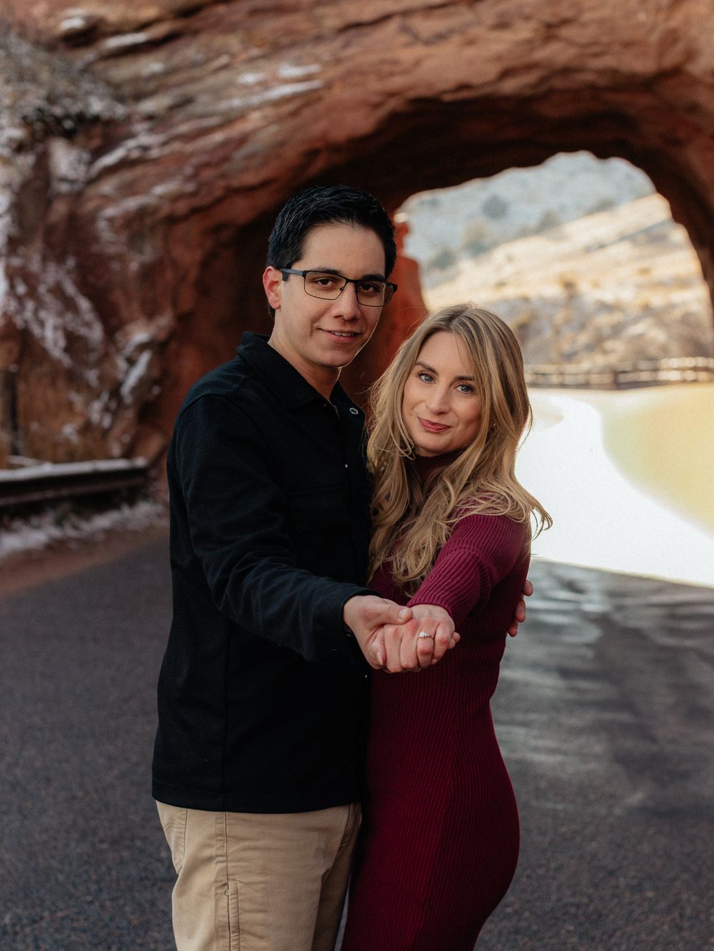 A couple shares romantic moments together under a rocky overhang during a winter photo session.