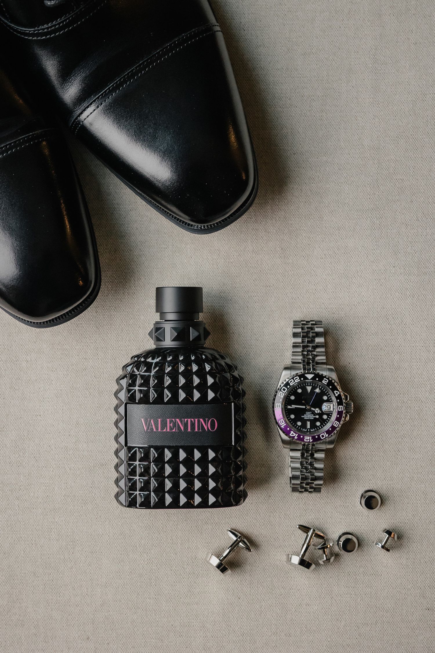 Valentino accessories and black dress shoes arranged on a light gray background.