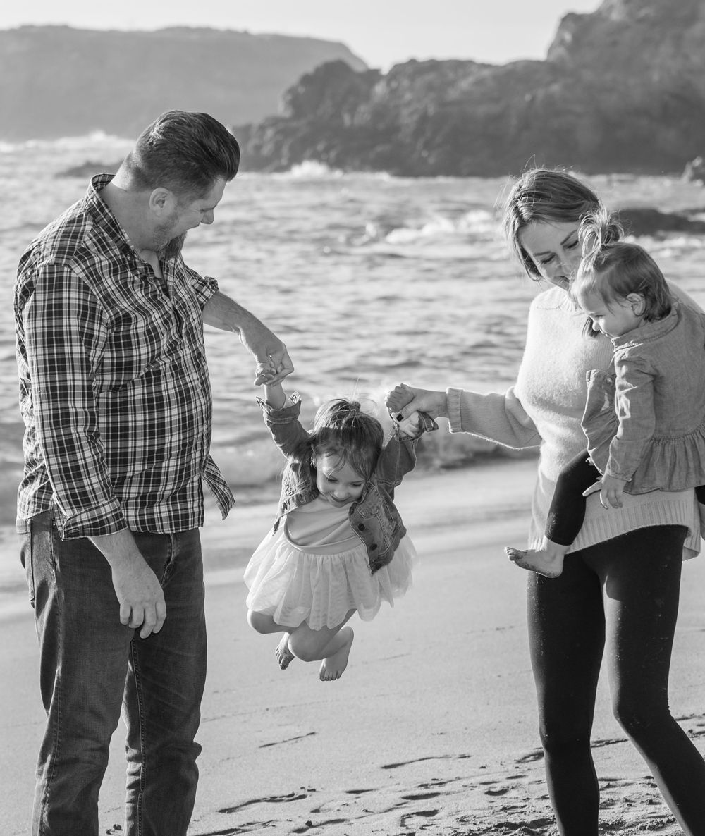 Black and white series of playful interactions between parent and child walking along a beach.
