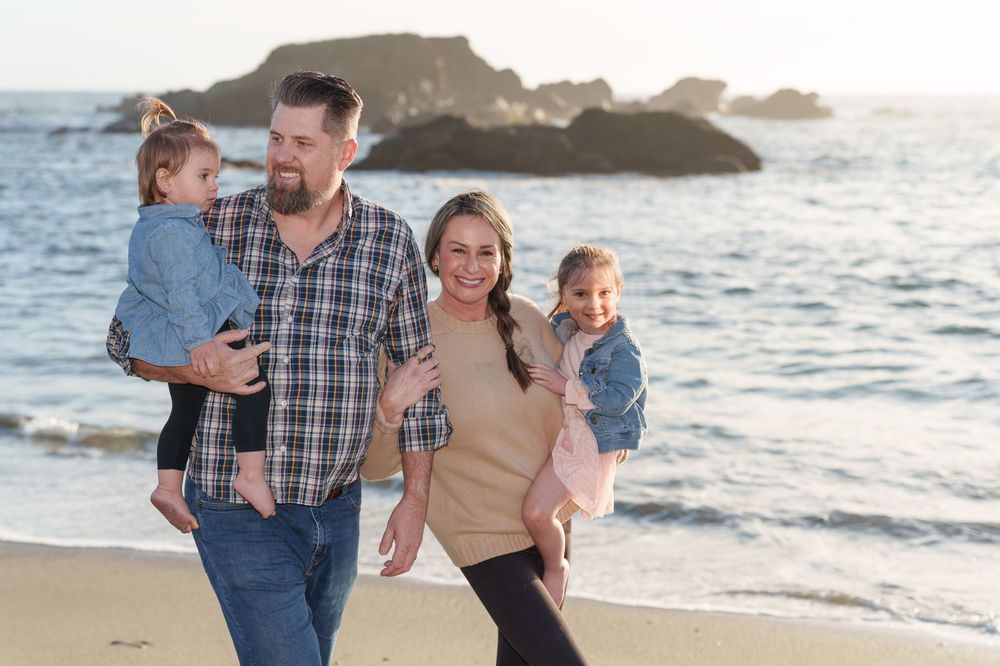 Family enjoying a sunset walk along the beach  in Sea Ranch with waves crashing in the background.