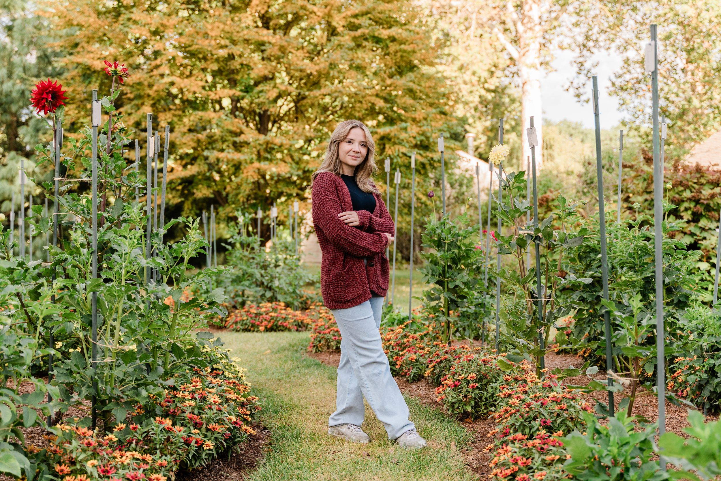 A garden path winds through vibrant fall foliage with red flowers and golden autumn leaves in the background.