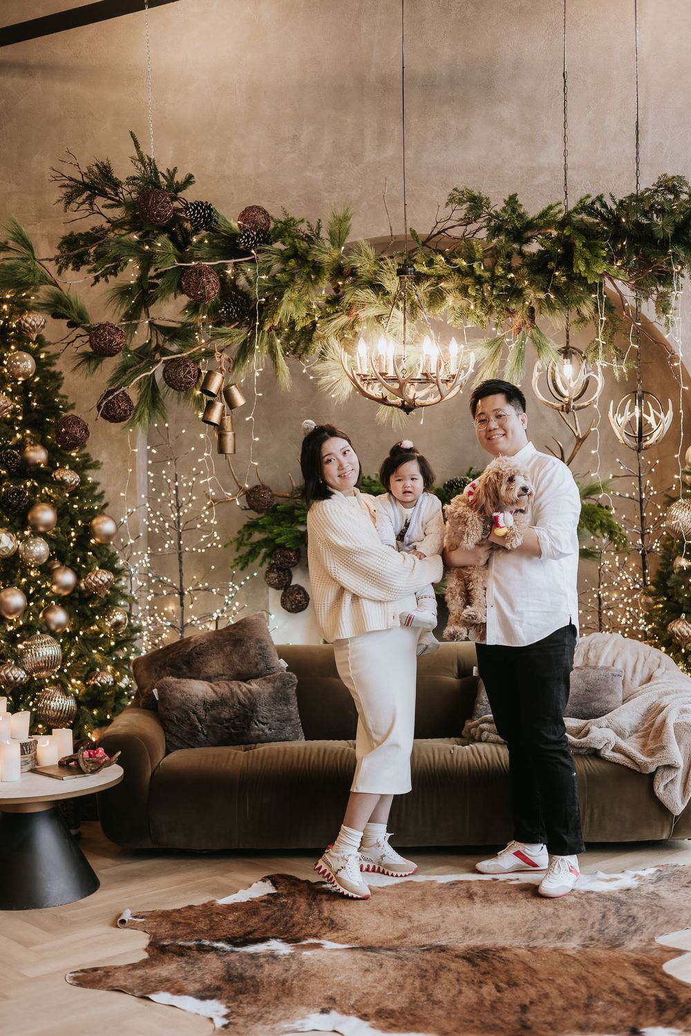 Family in white outfits having fun and playing together in a decorated room with twinkling lights and greenery.
