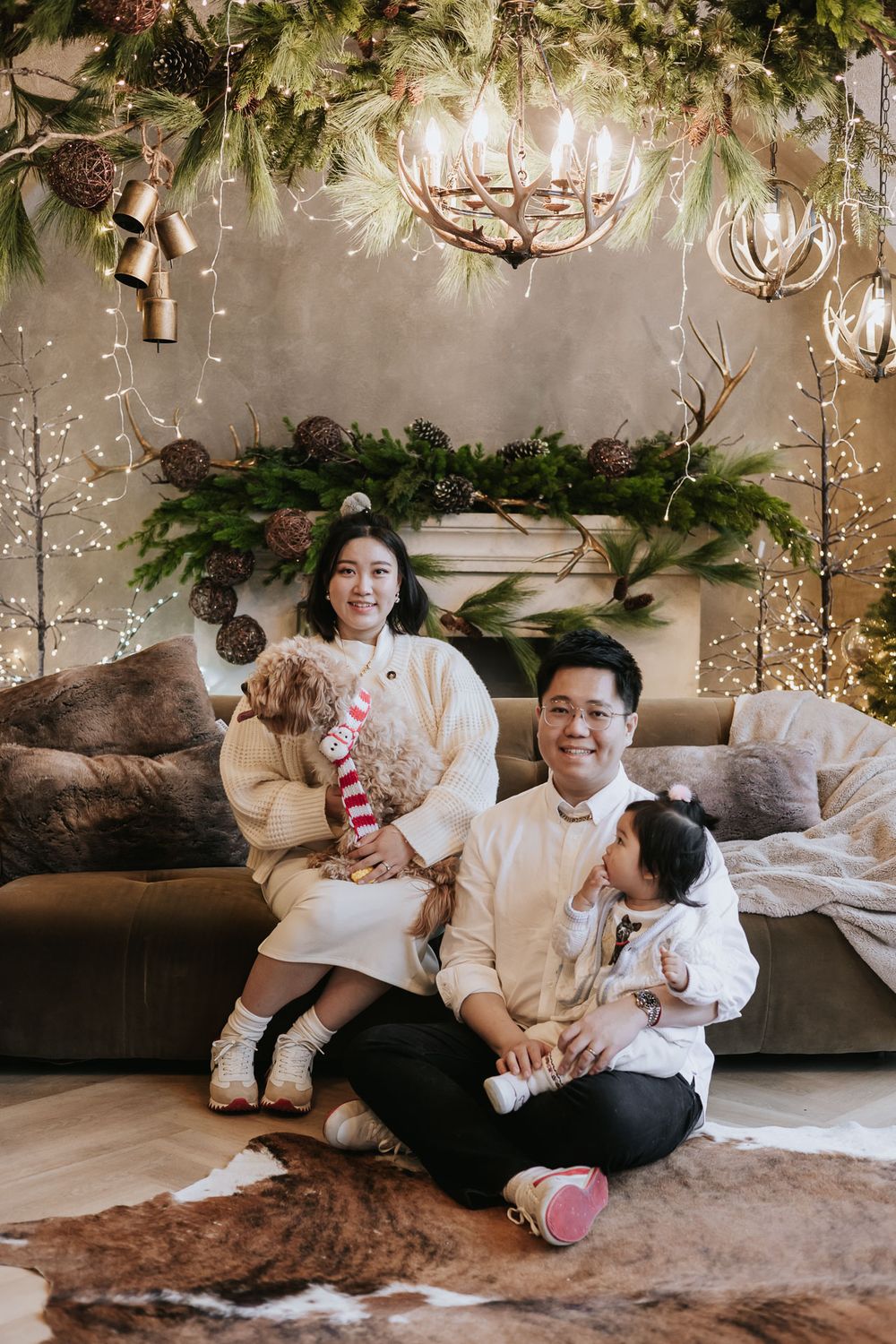 Family enjoying holiday moments together on a cozy couch decorated with festive greenery and twinkling lights.