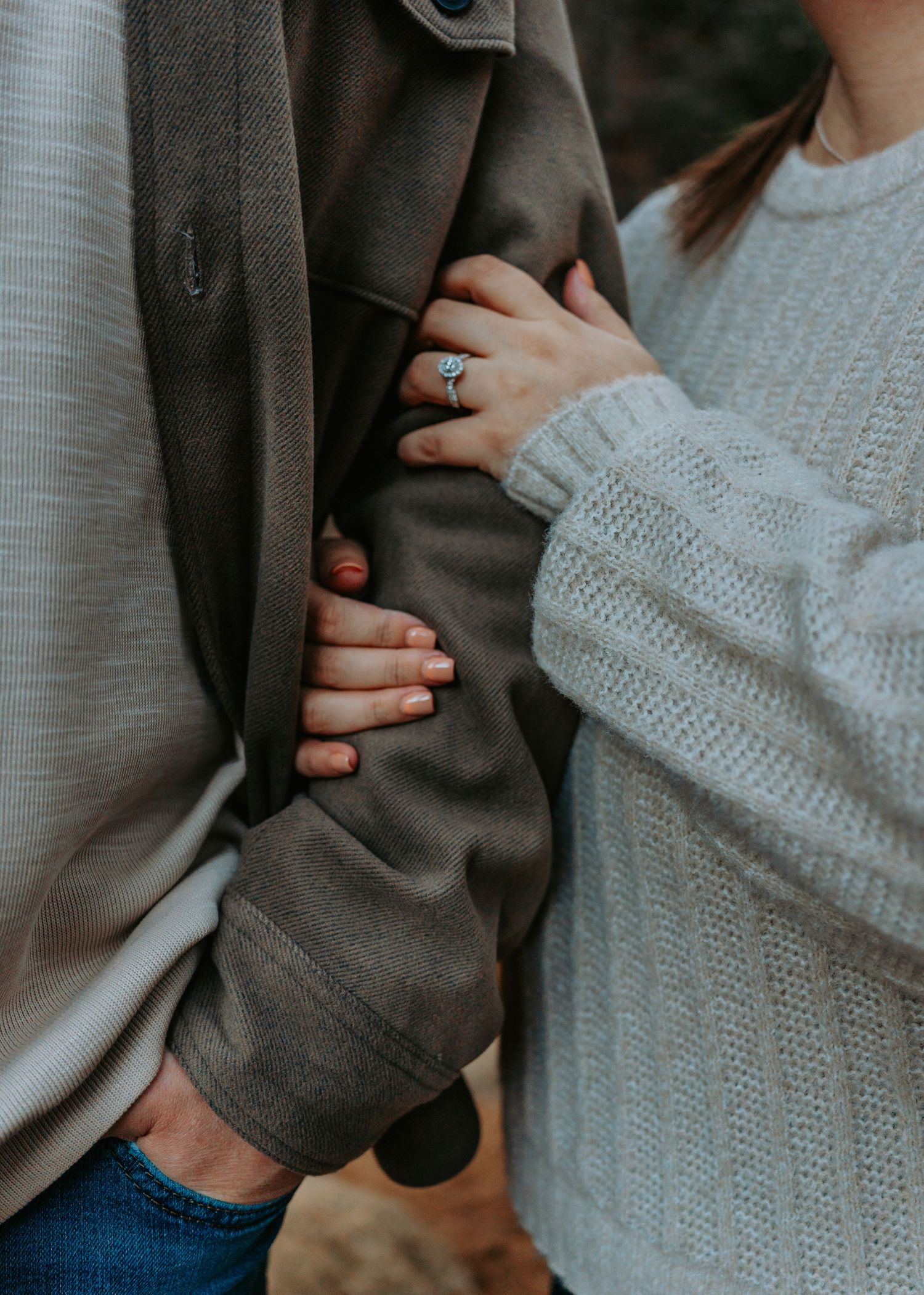 Close-up view of hands holding each other against a backdrop of gray and white knit clothing.
