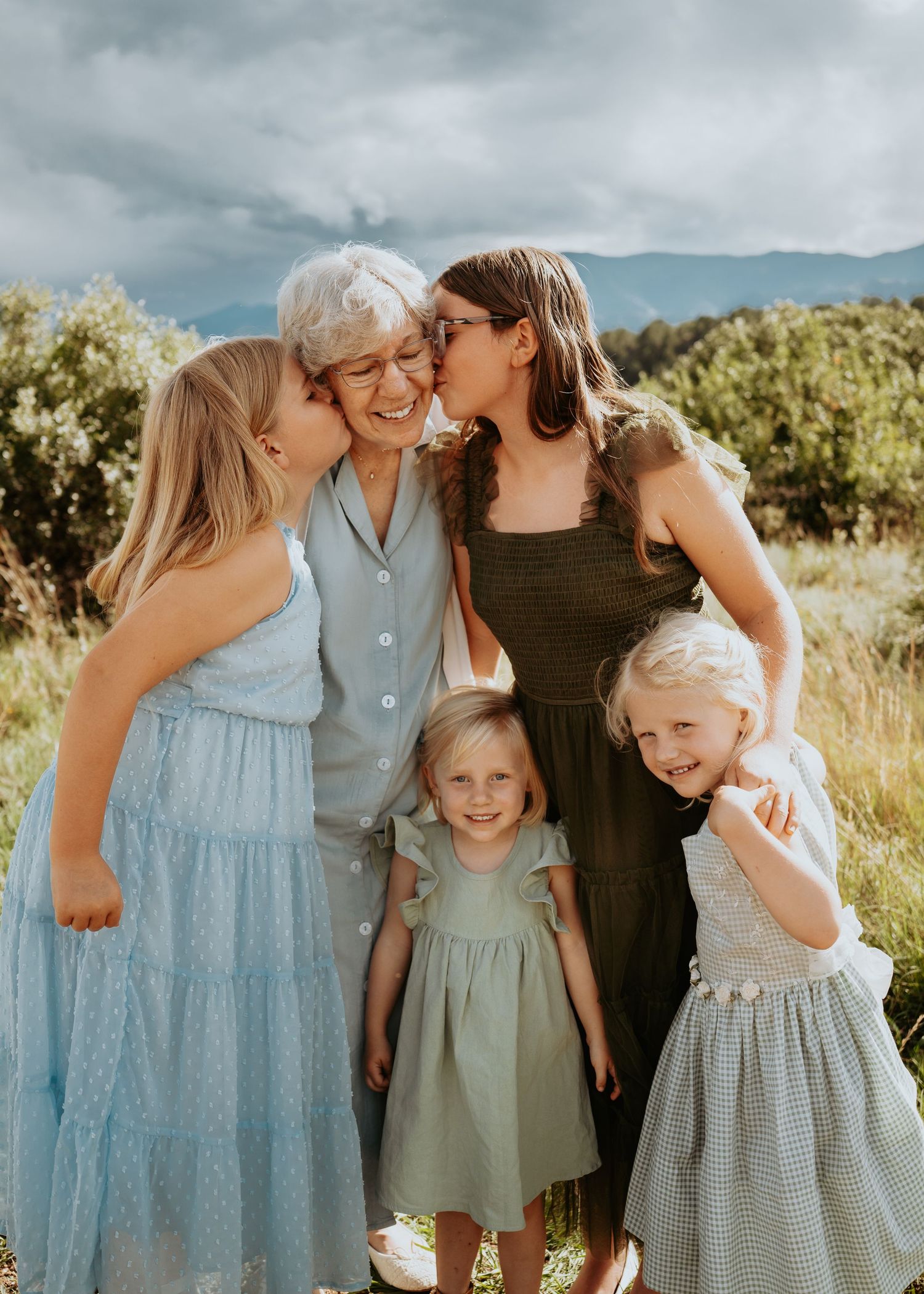 A sweet family moment captured in a series of outdoor photos with soft blue and green tones in a natural setting.