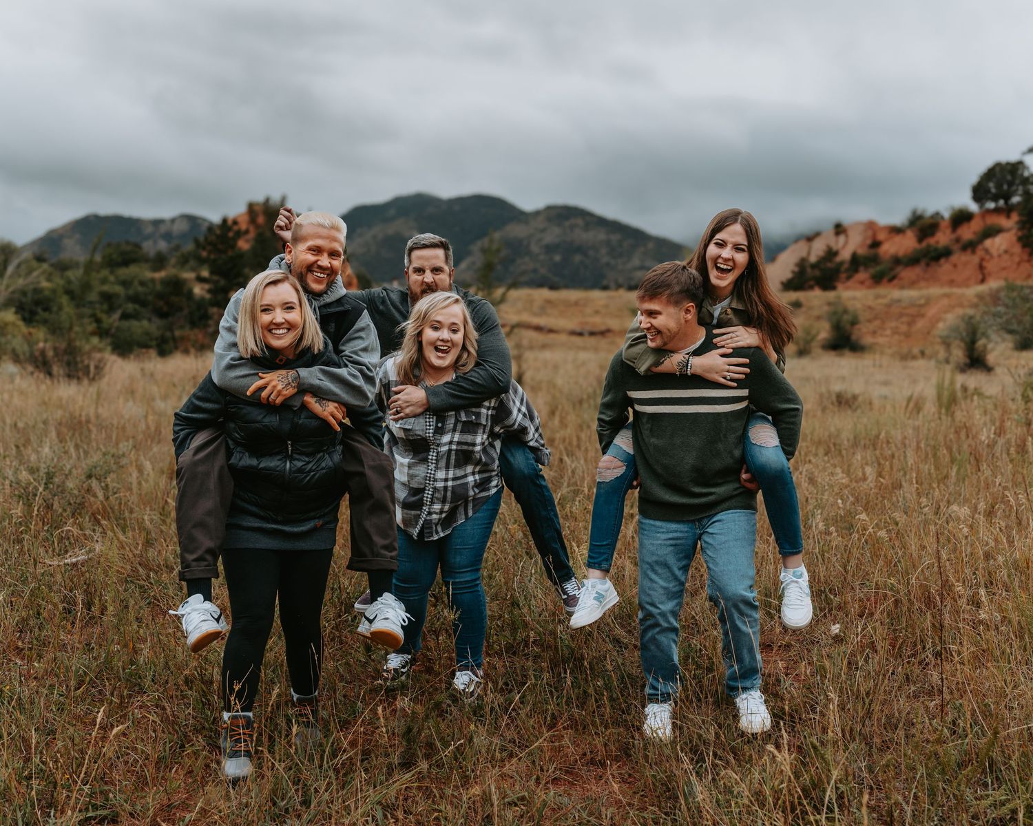 A group of friends having fun in a grassy field with mountains in the background, captured in a candid sequence.
