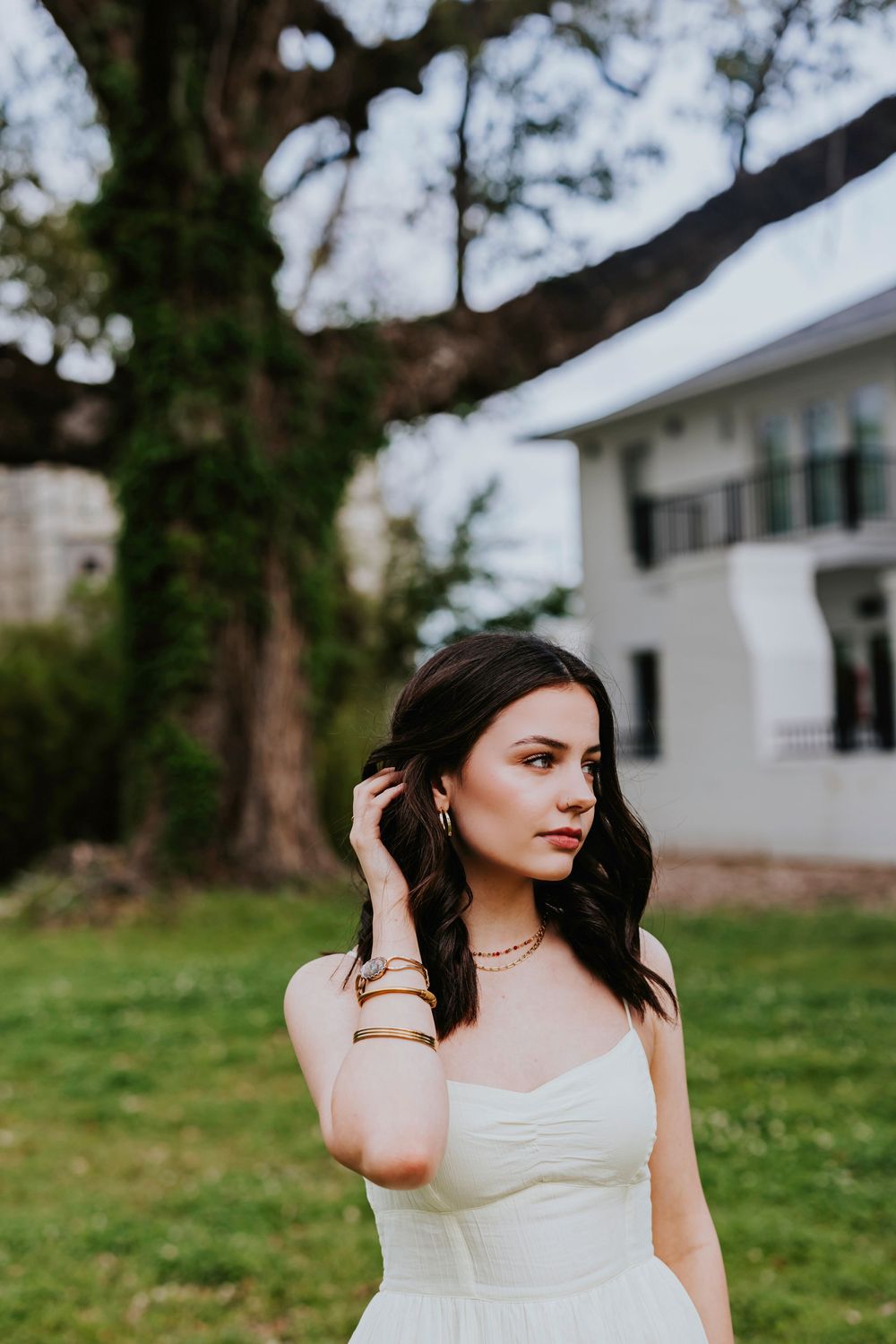 A dreamy portrait session in a grassy field with a white house visible in the background.