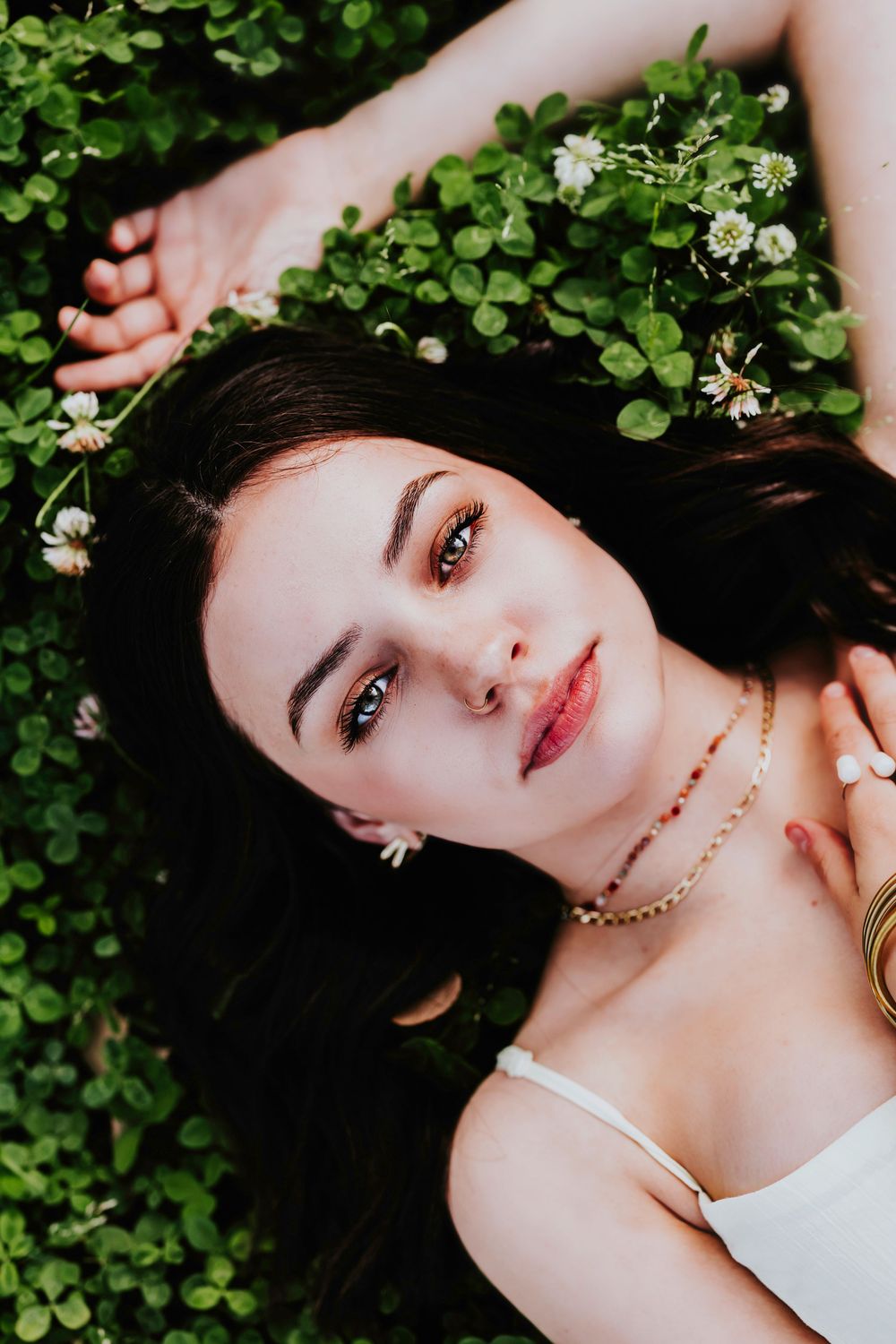 Artistic close-up portrait surrounded by delicate white flowers and green foliage.