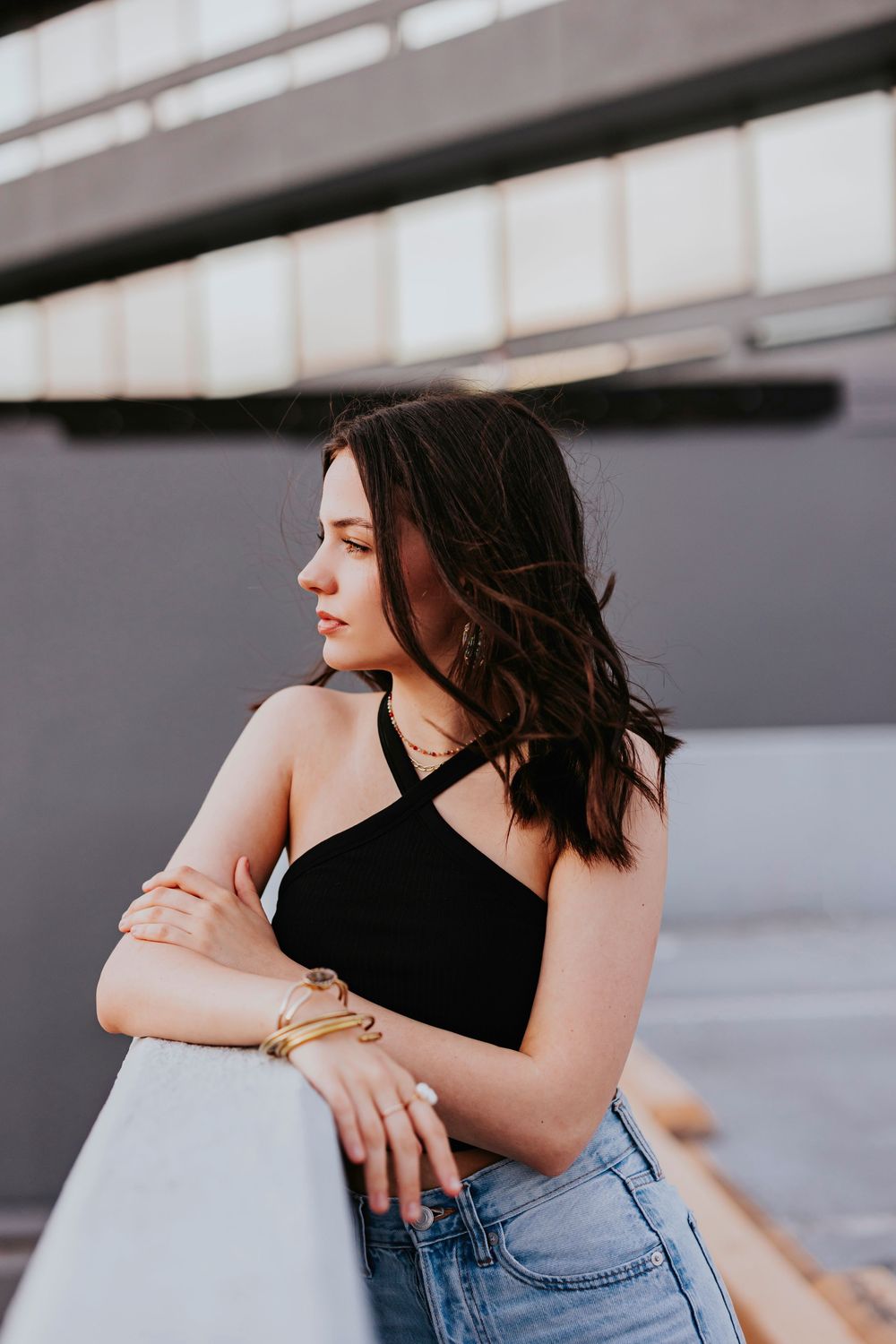 Artistic portrait series in black crop top and jeans against an industrial background.