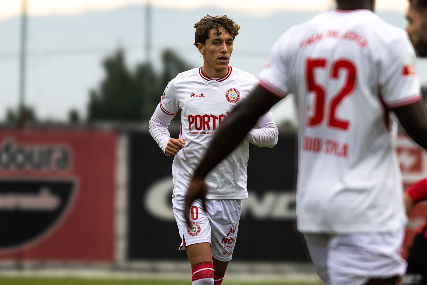 Soccer players in white uniforms spread across field during competitive match.