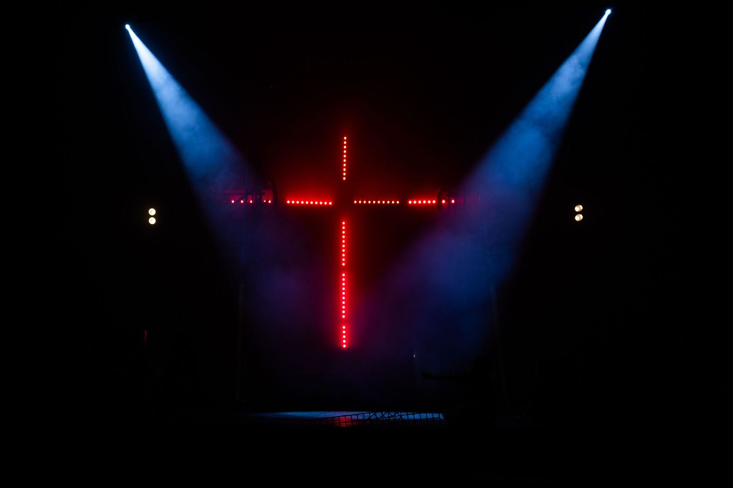 Stage lighting setup with blue and red cross-shaped lights in dark theater.