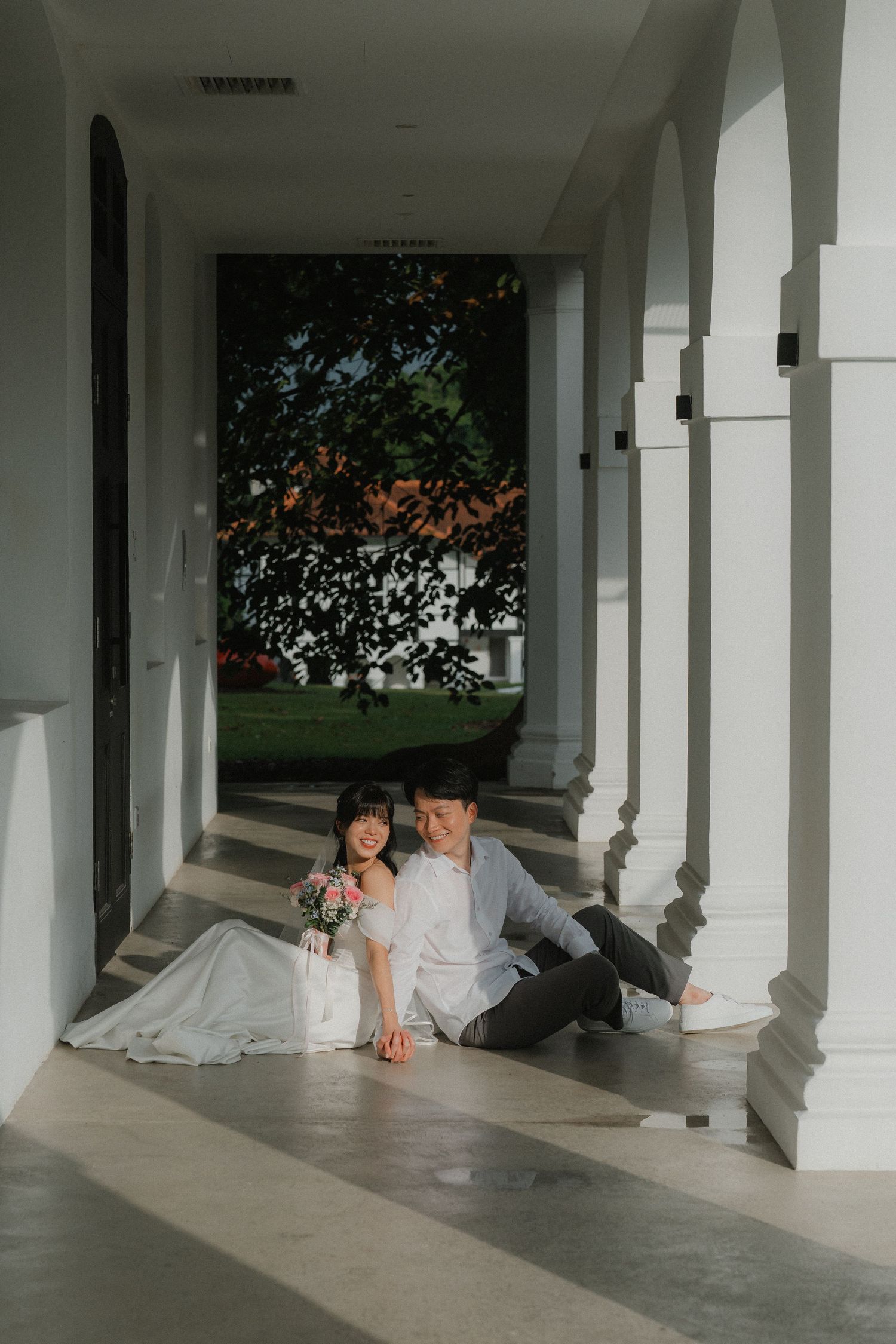 Artistic wedding photo series captured under white pillared walkway with natural lighting.