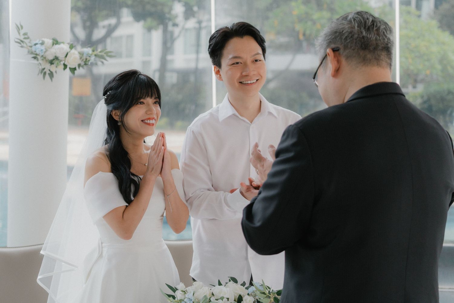 Intimate wedding ceremony moment with celebrant and couple in bright indoor setting.