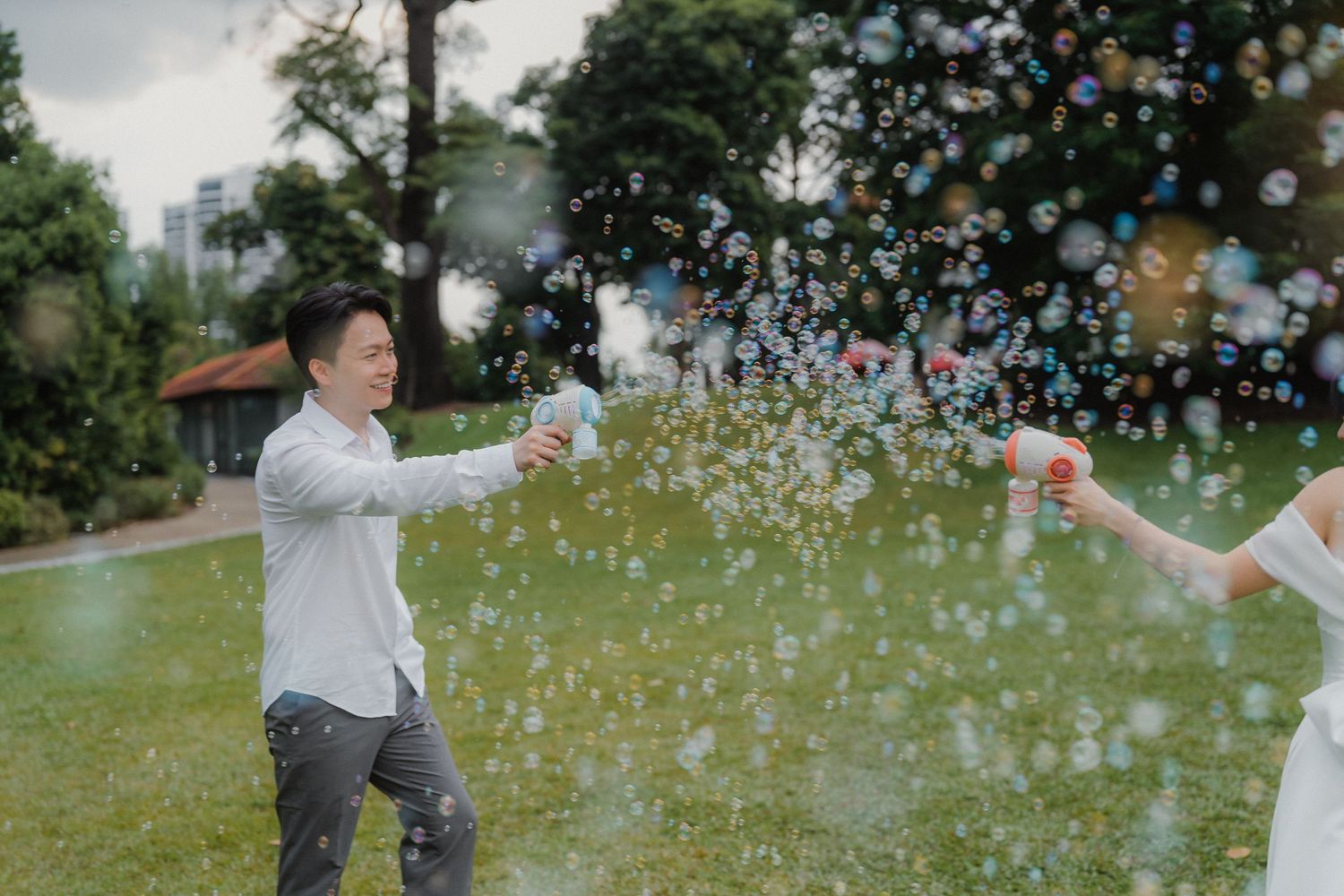 A joyful outdoor celebration with bubbles floating in the air during a wedding photoshoot.