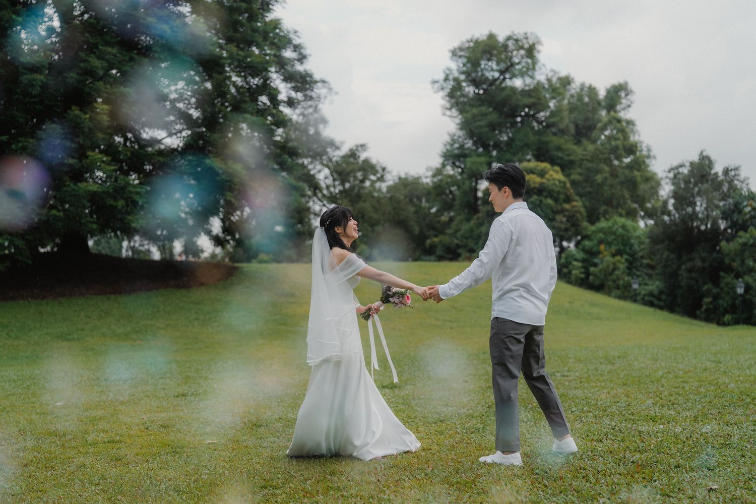 Couple playfully interacts on a misty green lawn during their wedding photo session.