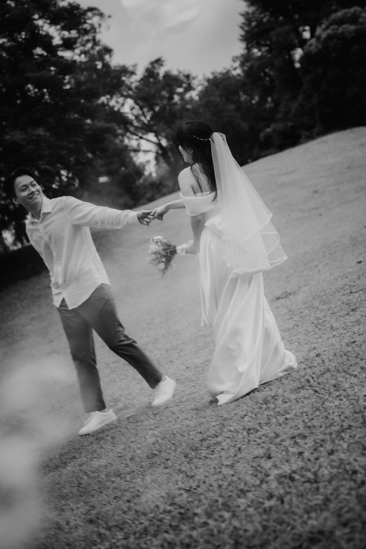 A black and white photo series shows a couple playfully running on a grassy hillside.