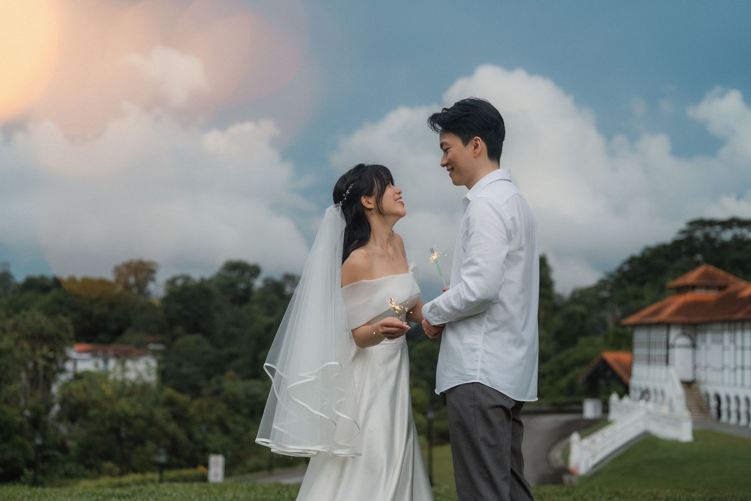A wedding couple shares an intimate moment against a cloudy sunset sky.