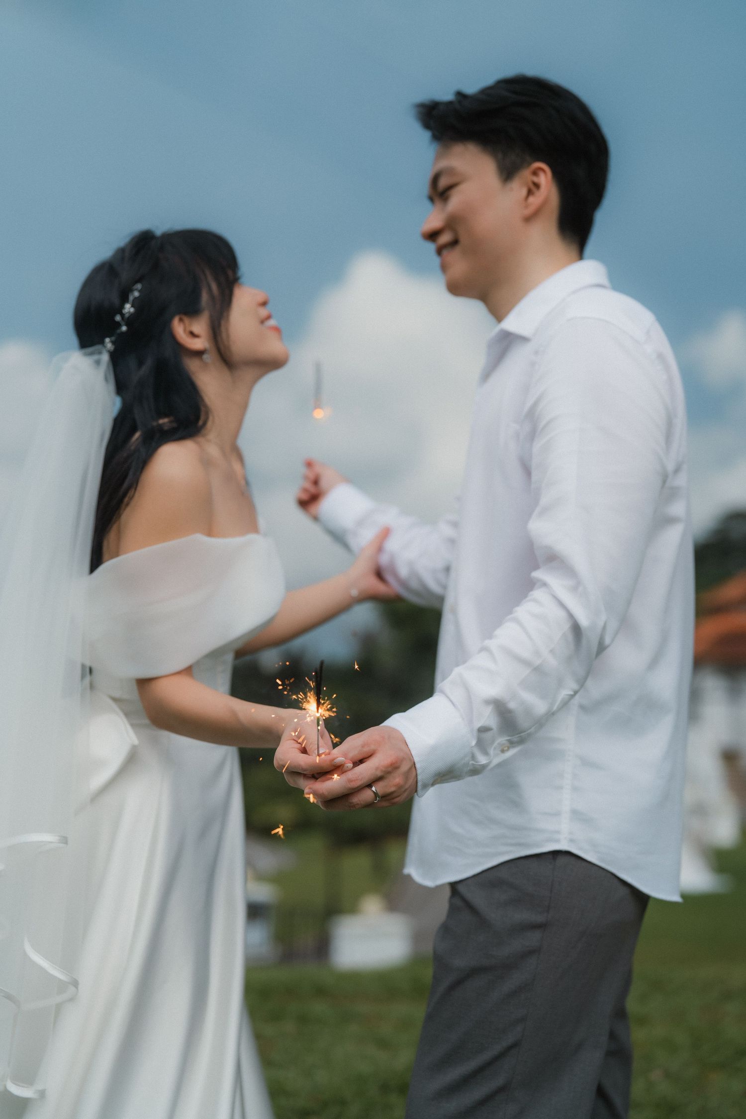 Wedding couple in white and grey sharing intimate moments while playing with sparklers.