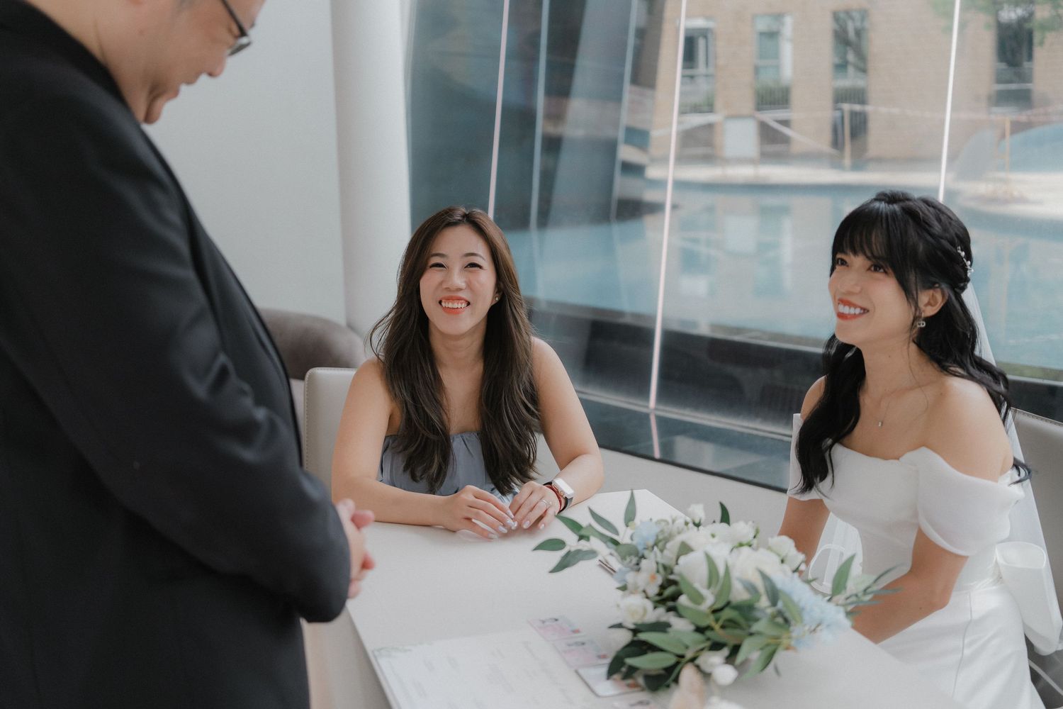 A casual wedding ceremony scene in an office setting with white decor and minimal floral arrangements.