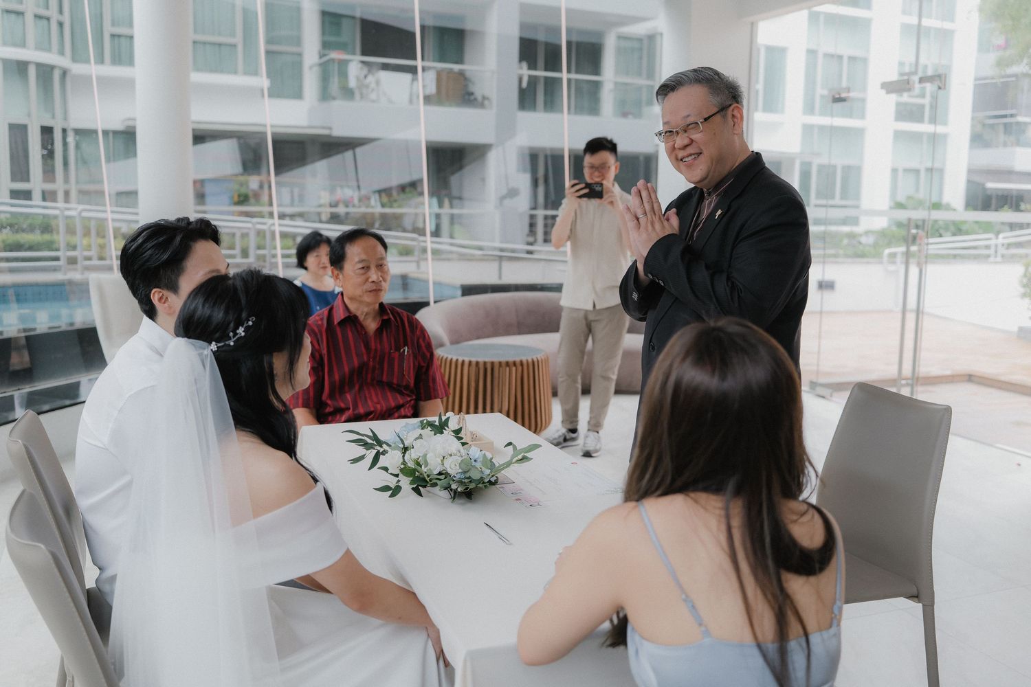 A wedding ceremony gathering with guests seated at a modern indoor venue.