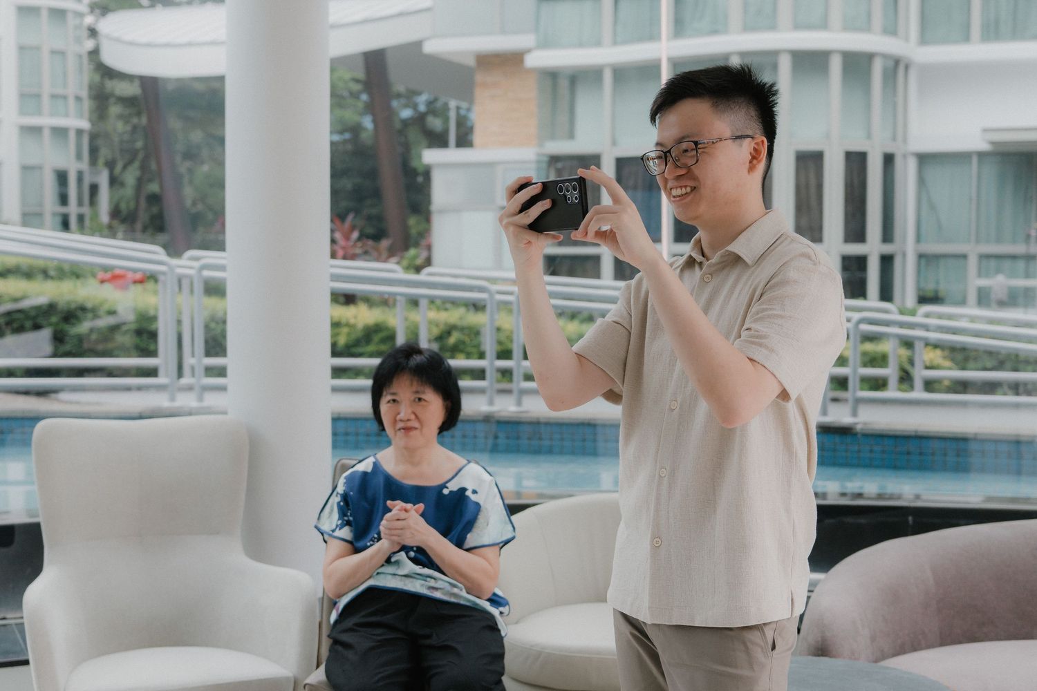 Photographers capturing moments at an elegant venue with glass windows and outdoor pool views.