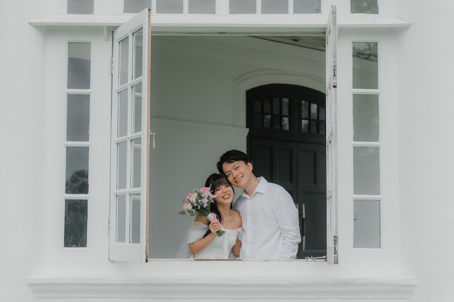 A minimalist white exterior building features matching windows with elegant shutters.